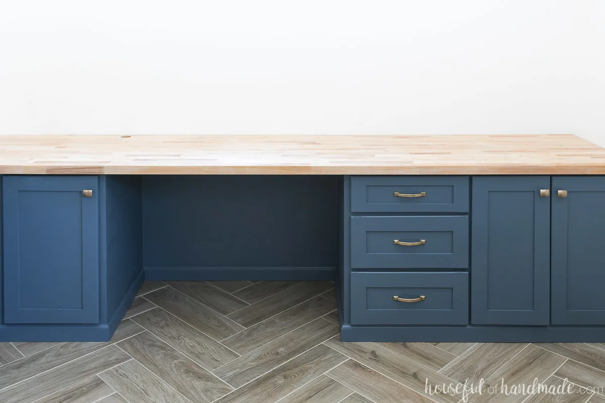 Blue build in desk cabinets with light colored wood top. 