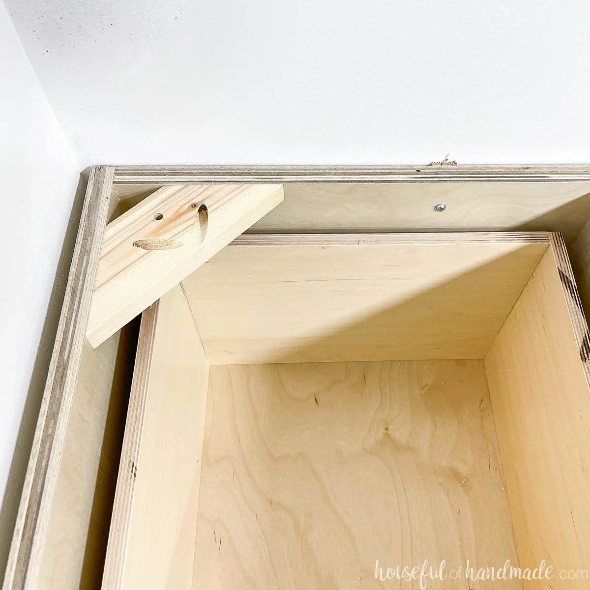 A scrap piece of wood attached to the top corner of the cabinet to attach the countertop to.