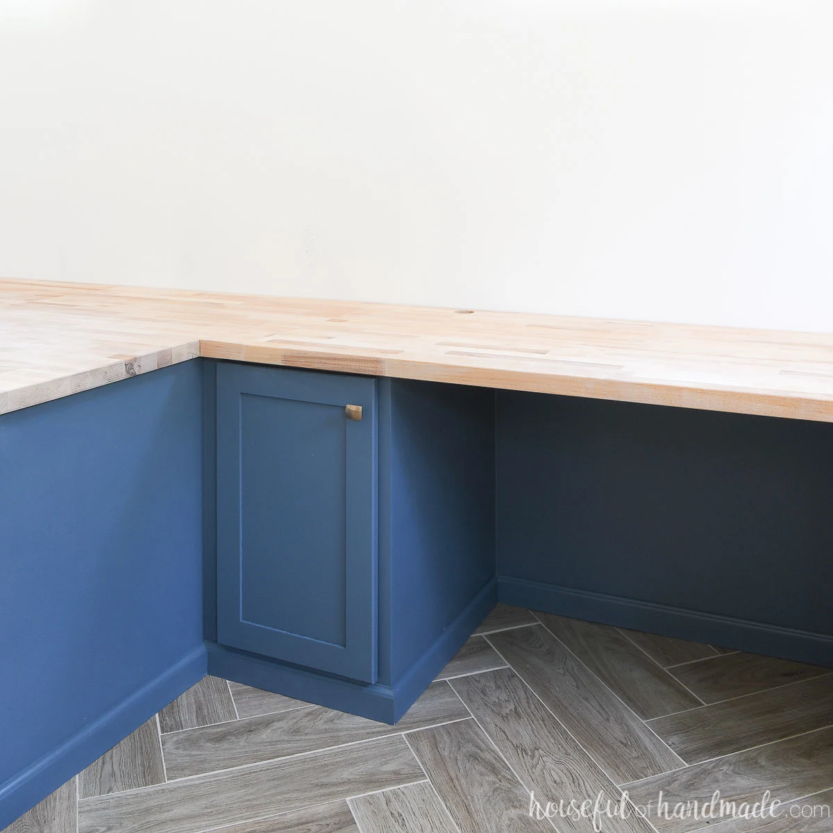 Corner of a built in desk with NYPD blue cabinets and wood countertop. 