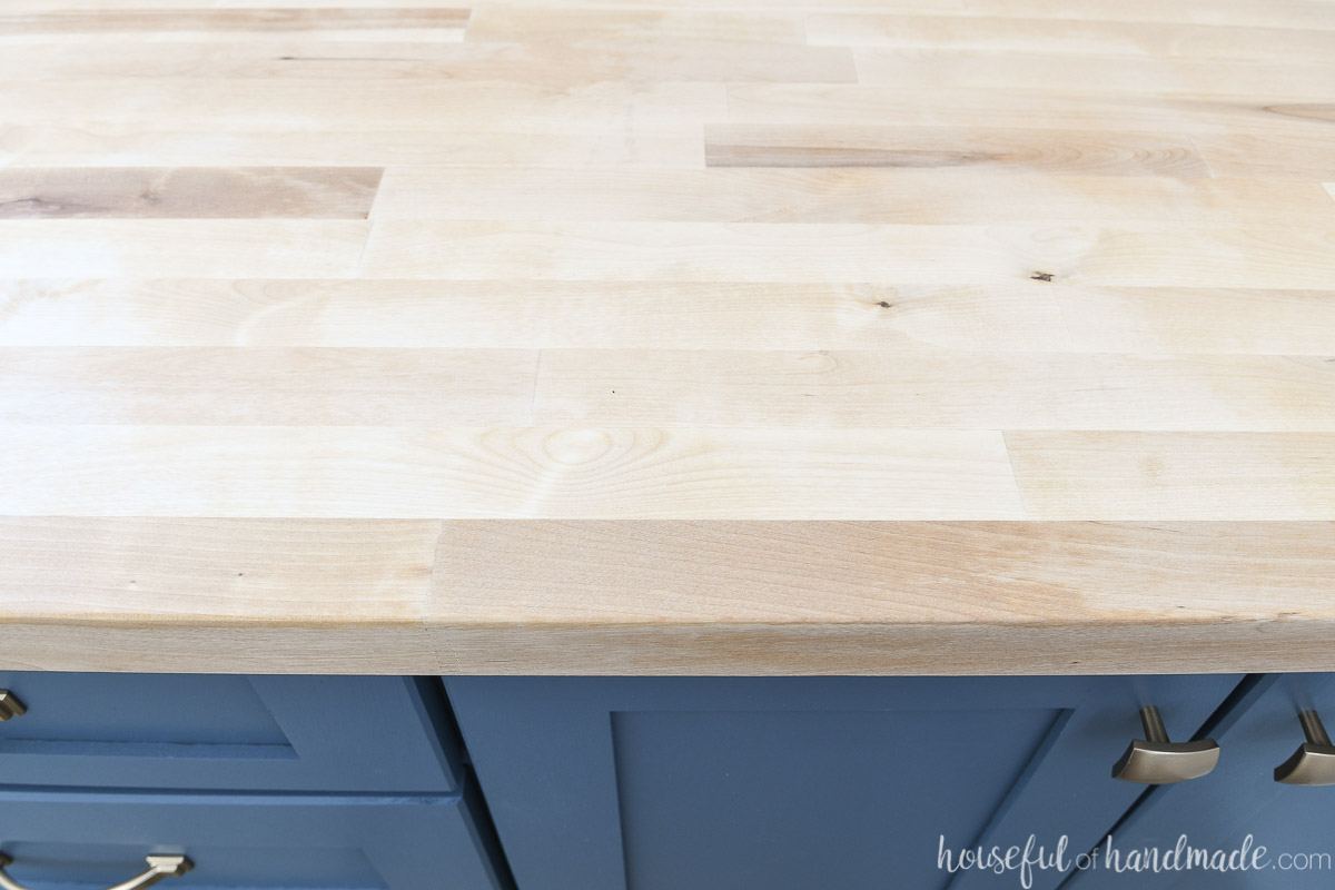 Top down view of the matte, unfinished look of the sealer on the butcher block countertop over blue cabinets. 