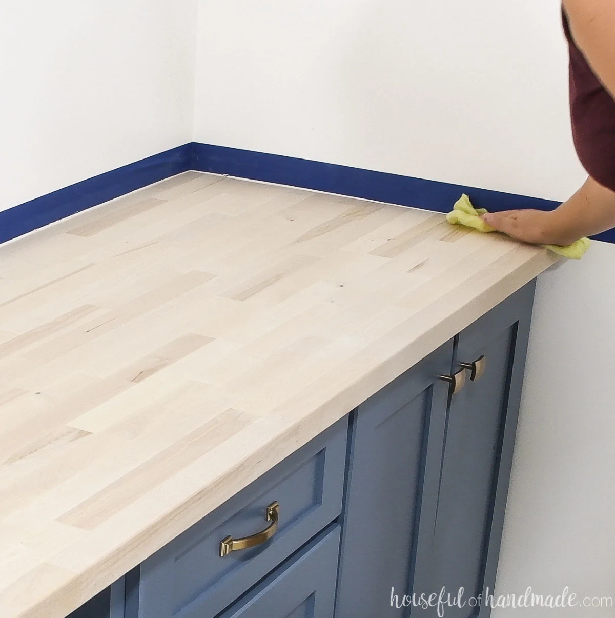 Using a tack cloth to remove the final dust from the surface of the countertop before sealing. 