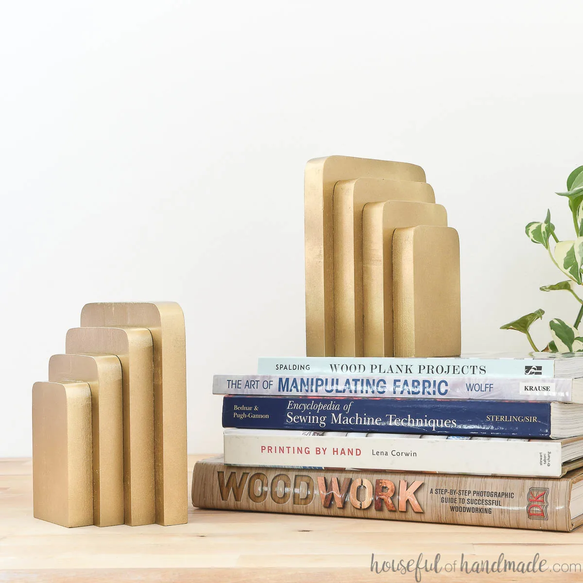 Two bookends made from wood displayed on top of a stack of books. 