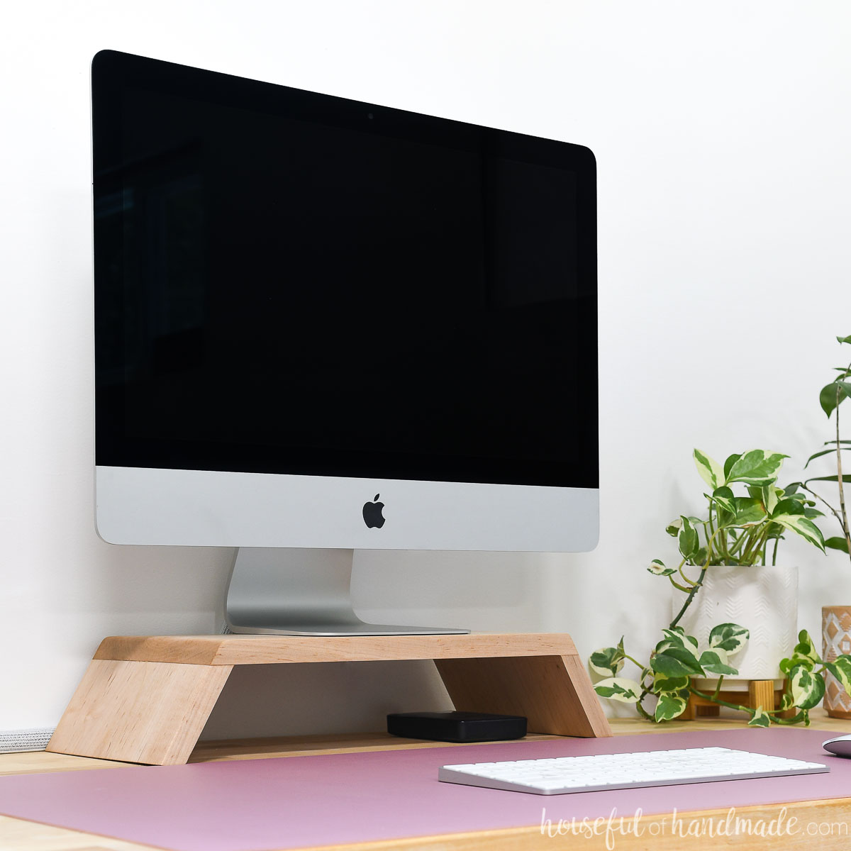 DIY monitor stand made from scrap wood with an iMac on top of it on a desk.