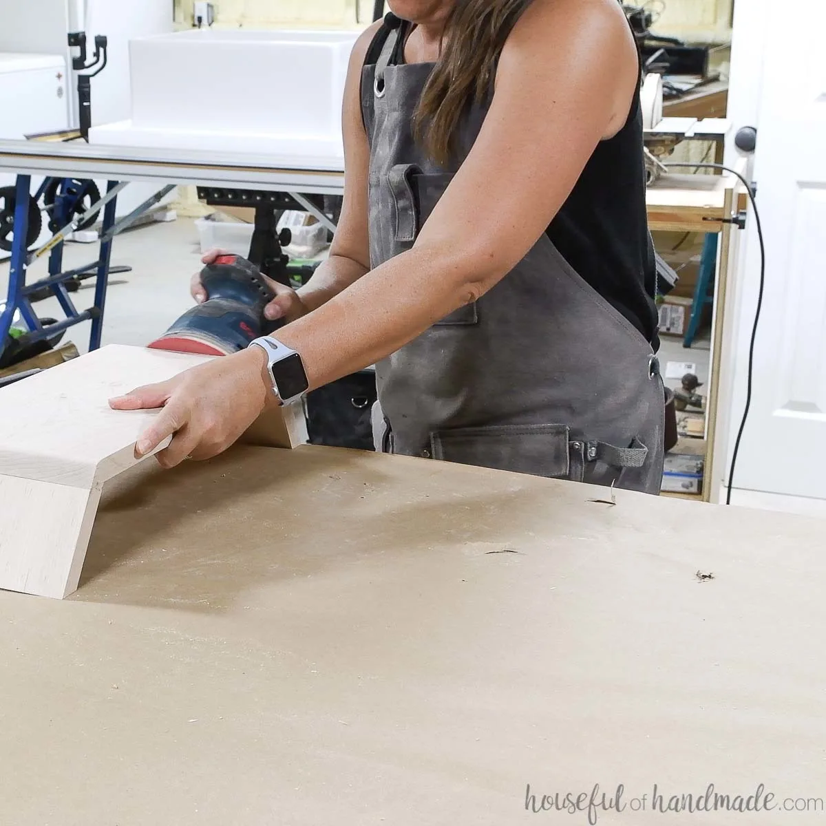 Sanding the DIY monitor stand with an orbital sander. 