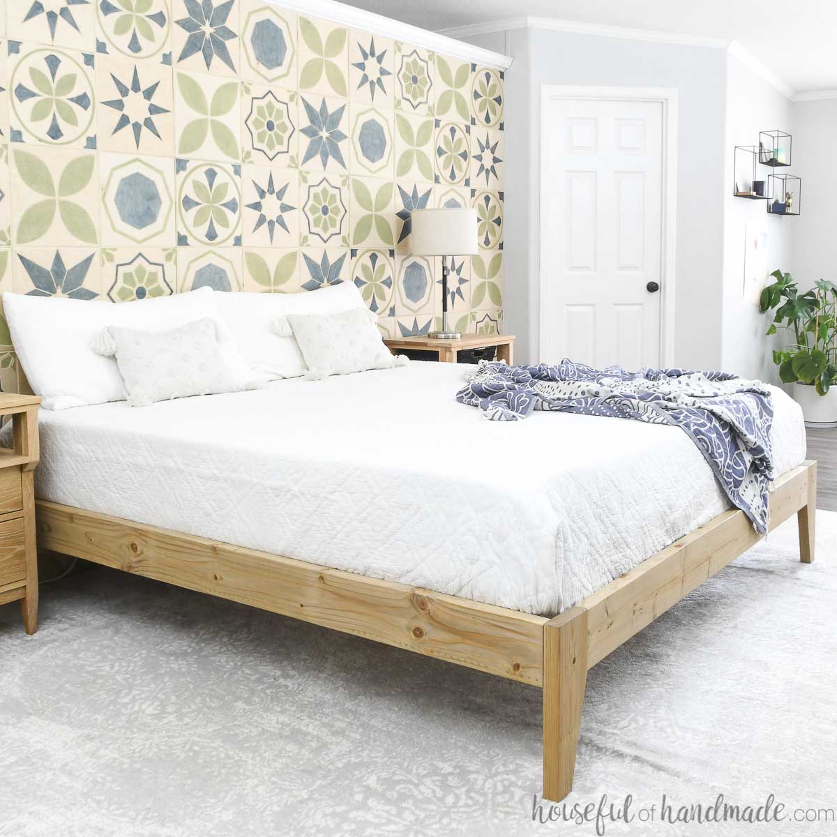 DIY platform bed frame with mattress in a brightly lit bedroom.