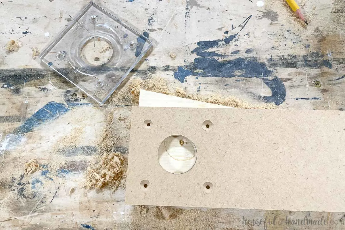 Piece of MDF with identical markings to the plastic router plate next to it. 