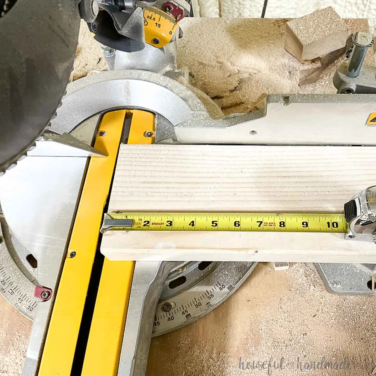 Measuring a piece of 2x6 board sittingon a miter saw. 