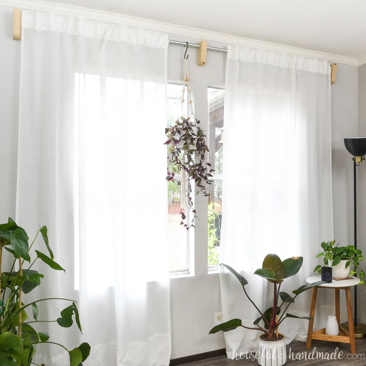 Room full of plants and white sheer curtains hung with DIY scrap wood curtain rod brackets. 