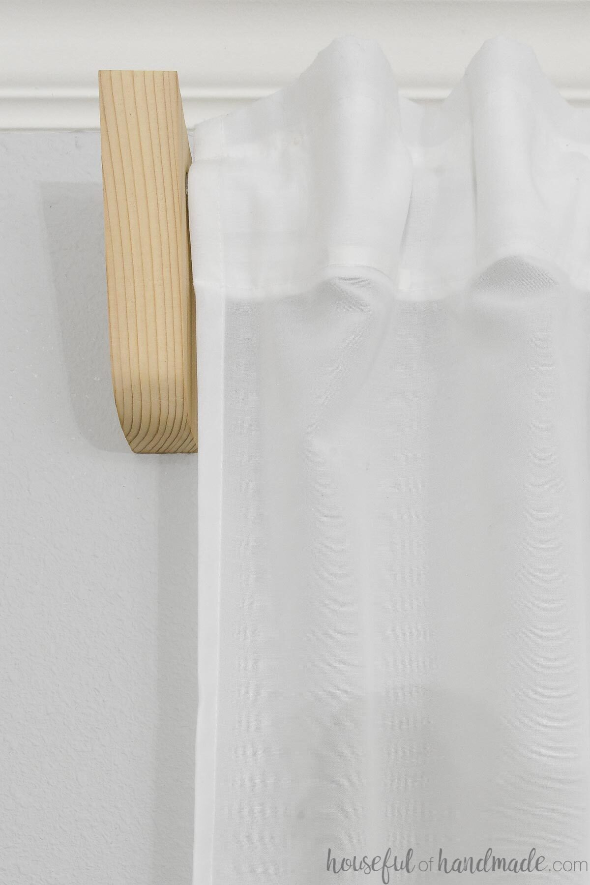 Close up of a simple curtain rod bracket made from a 2x6 board. 