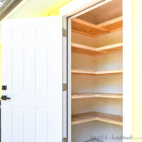 Closet door open showing DIY storage shelves in an L around the walls.