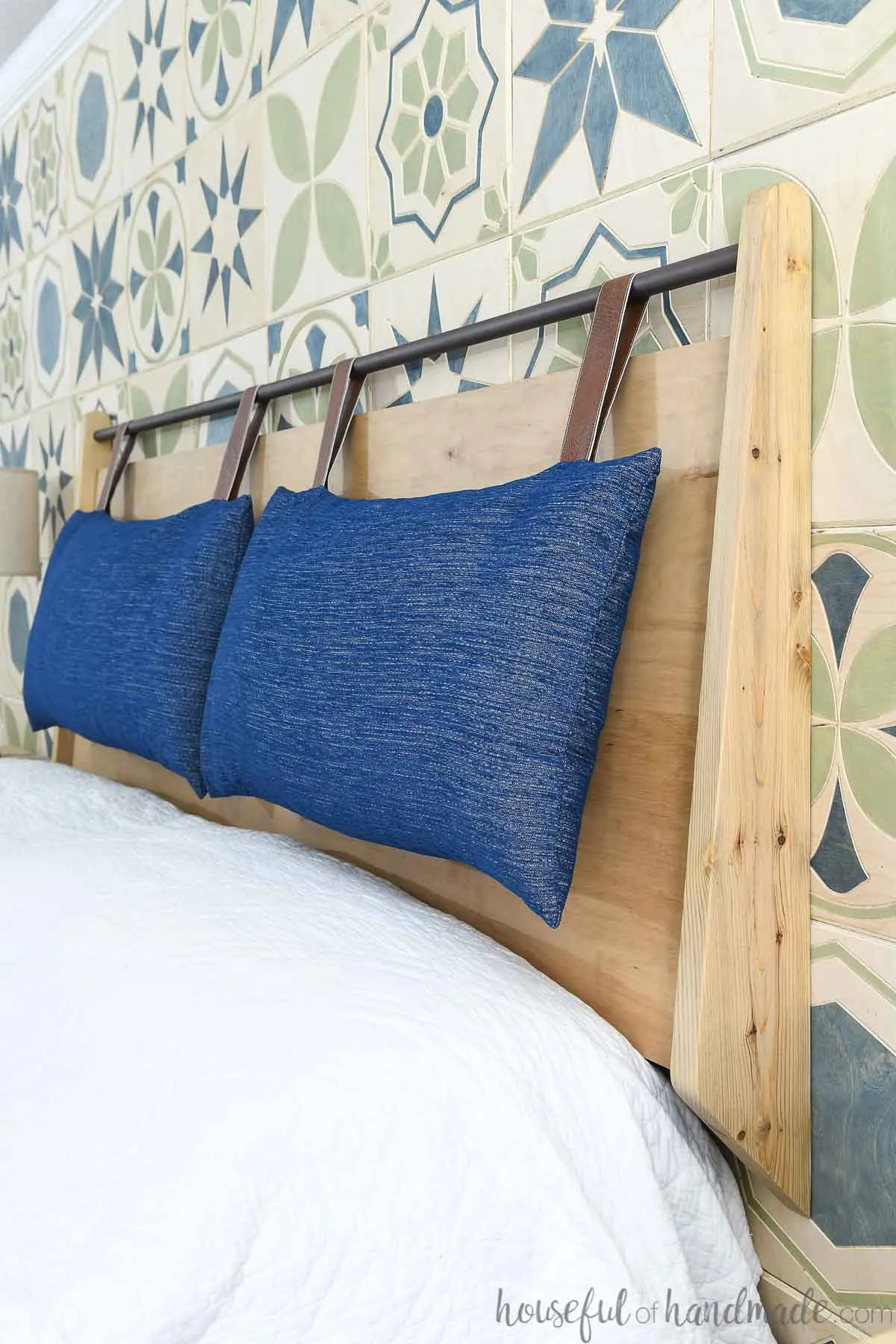 Wall-mounted headboard with an angled back and hanging cushions on a wood tile wall. 