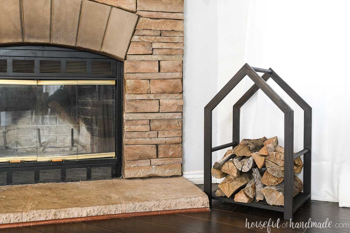 Fireplace hearth made from stones with a black modern firewood rack next to it. 