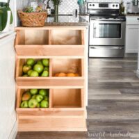 Six compartment wooden vegetable storage bin that fits on the end of a kitchen cabinet.
