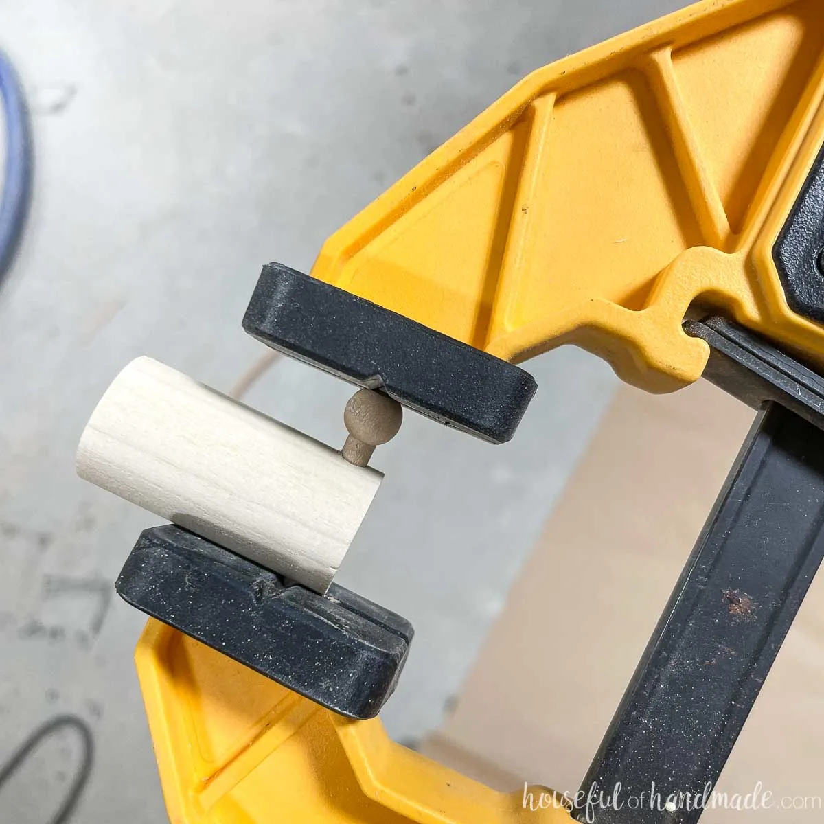 Squeezing a tie rack pin into the hole with a wood clamp. 