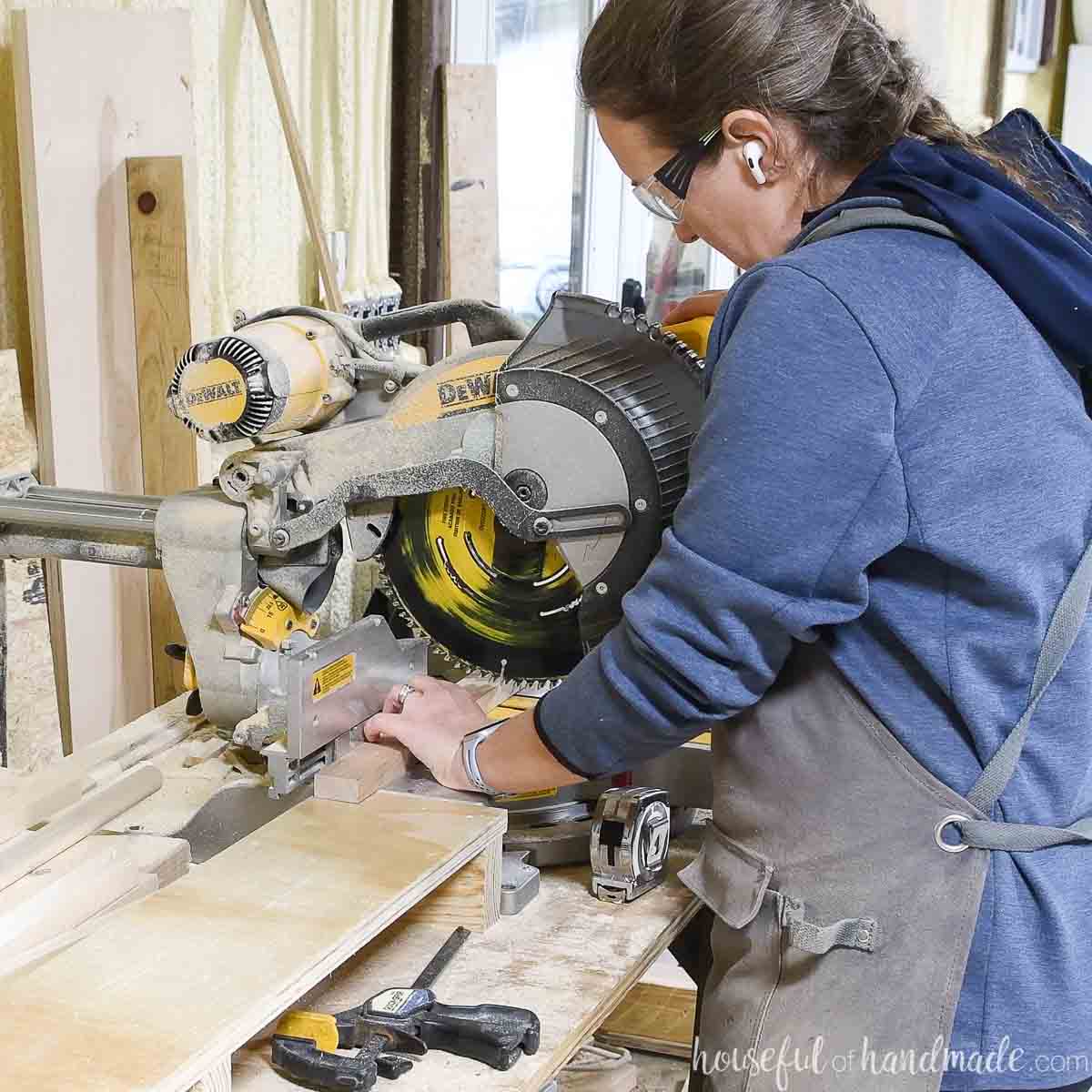 Girl cutting a 1x2 on a miter saw. 