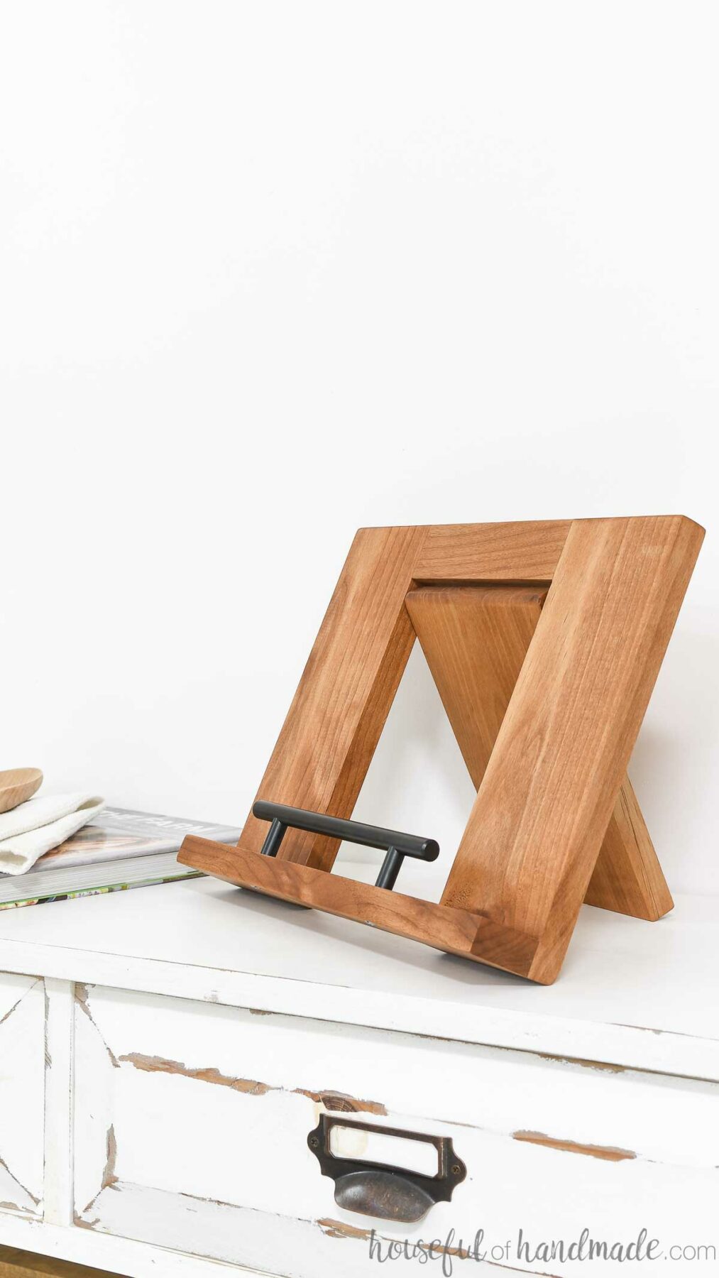 Alder wood folding cookbook holder sitting on a console without a cookbook on it. 