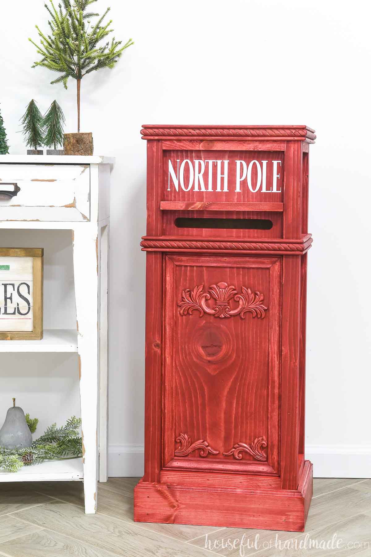 Red stained wood Santa mailbox with North Pole in white on the top. 