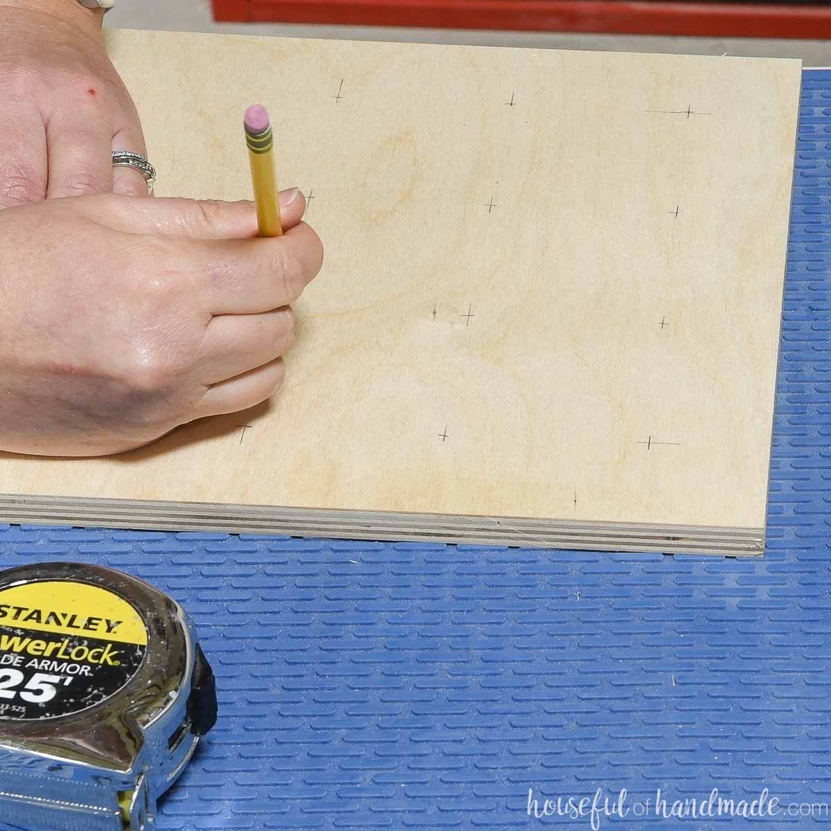 Marking center points for holes on a piece of plywood. 