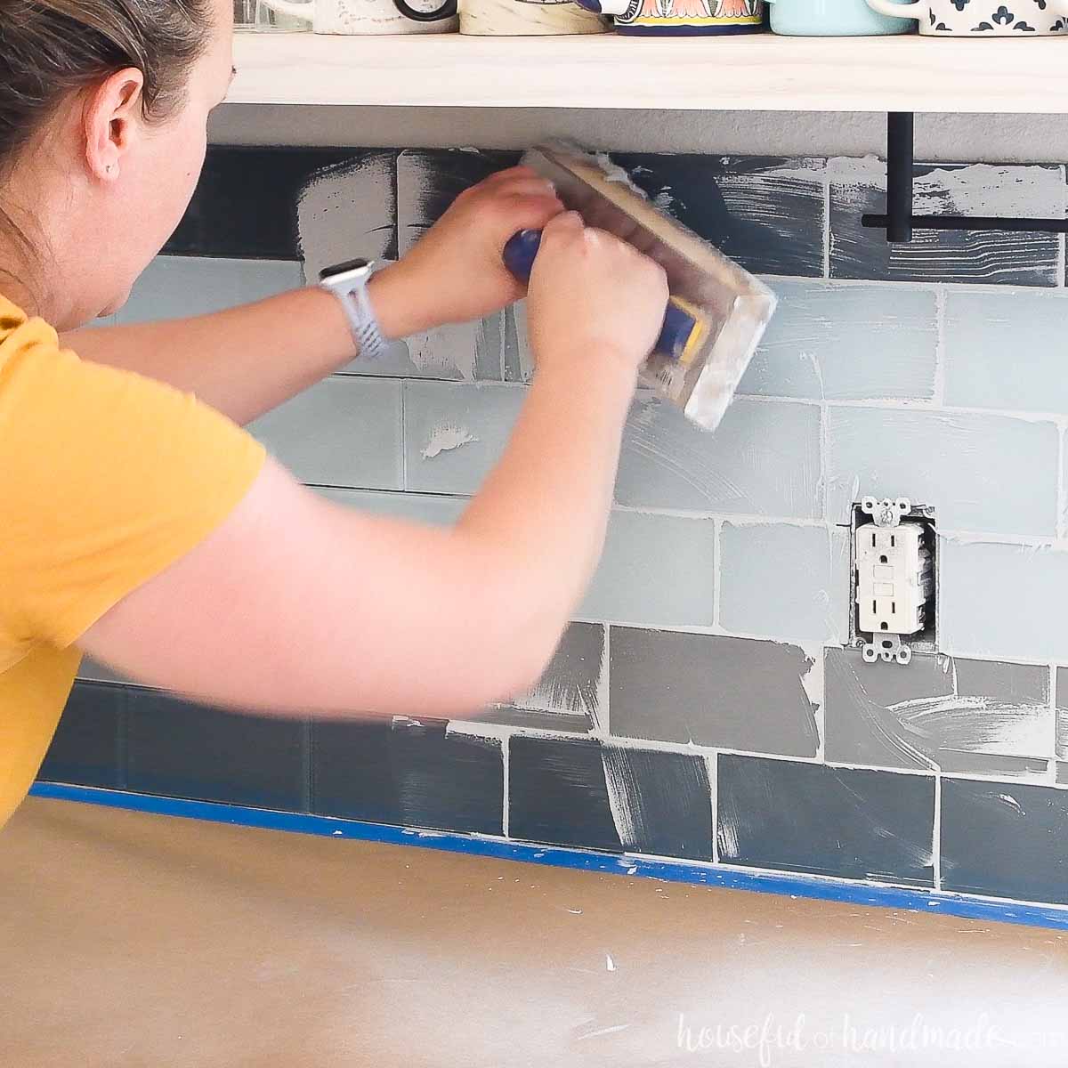 Girl pressing grout into joint lines with a rubber float.