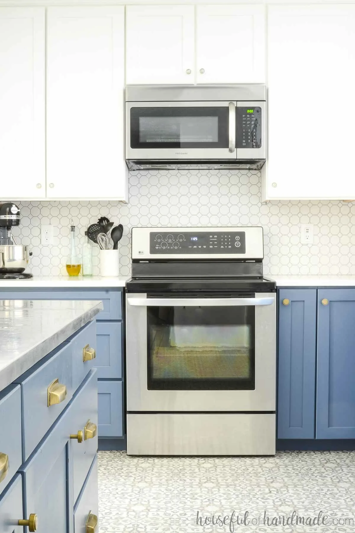 Kitchen with white upper cabinets and blue lower cabinets and skinny spice cabinet next to stove. 