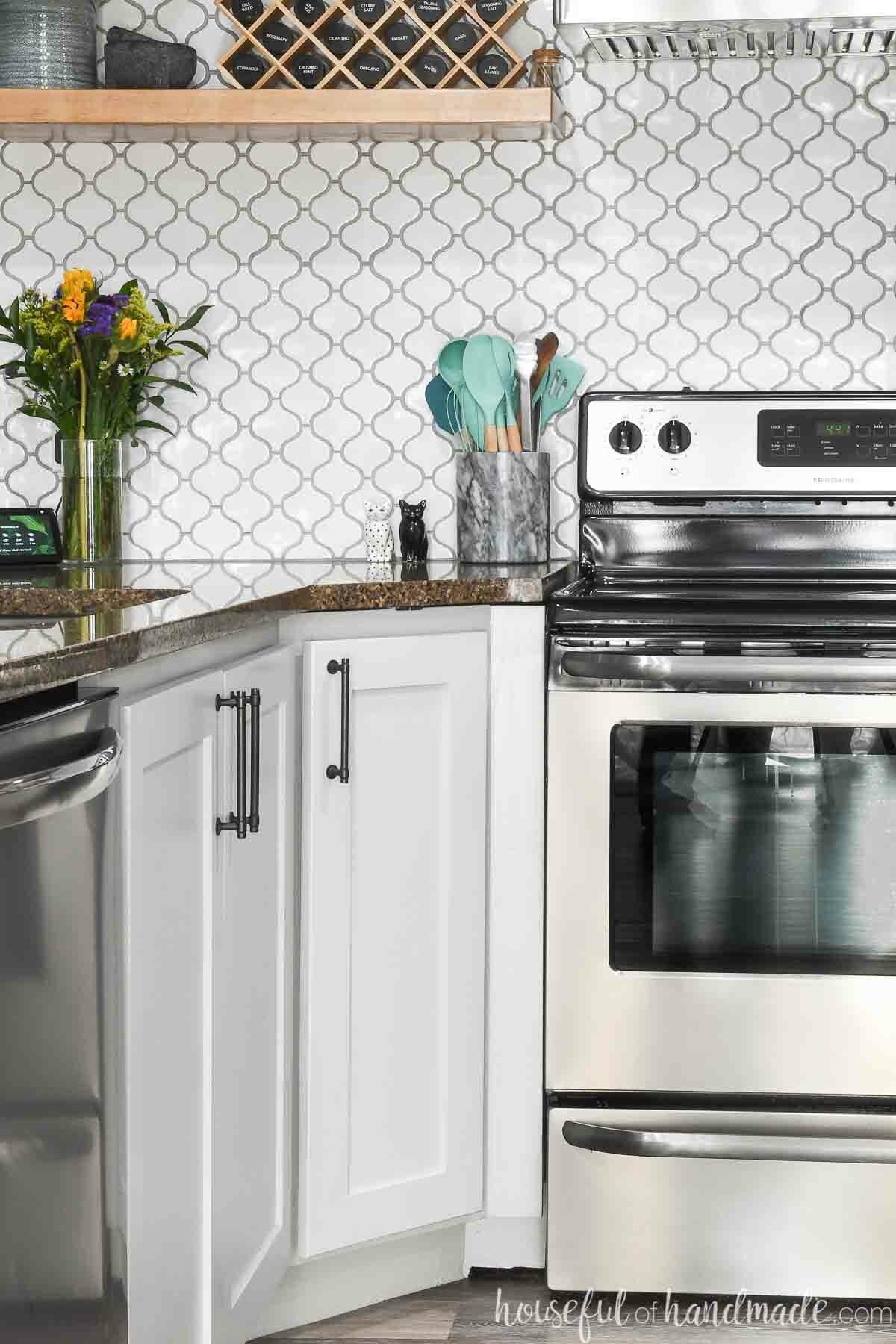 Diagonal corner base cabinet in a kitchen next to a stove. 