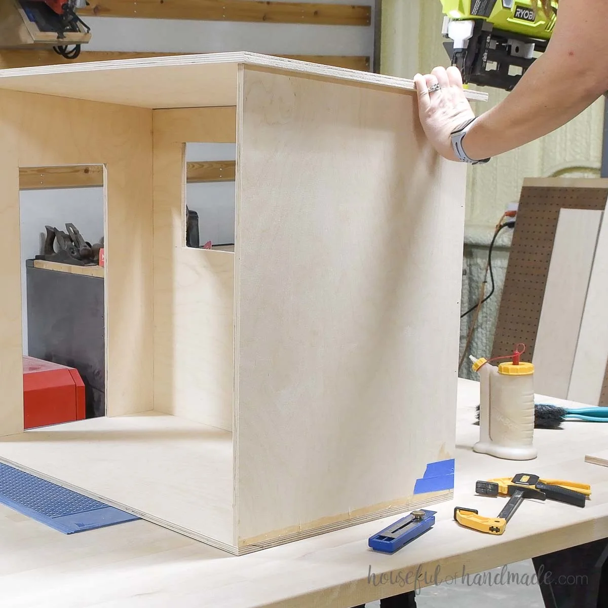 Attaching the dollhouse roof with a finishing nailer. 