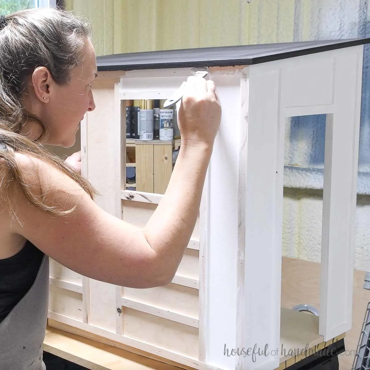 Painting the outside walls of the stable dollhouse white. 