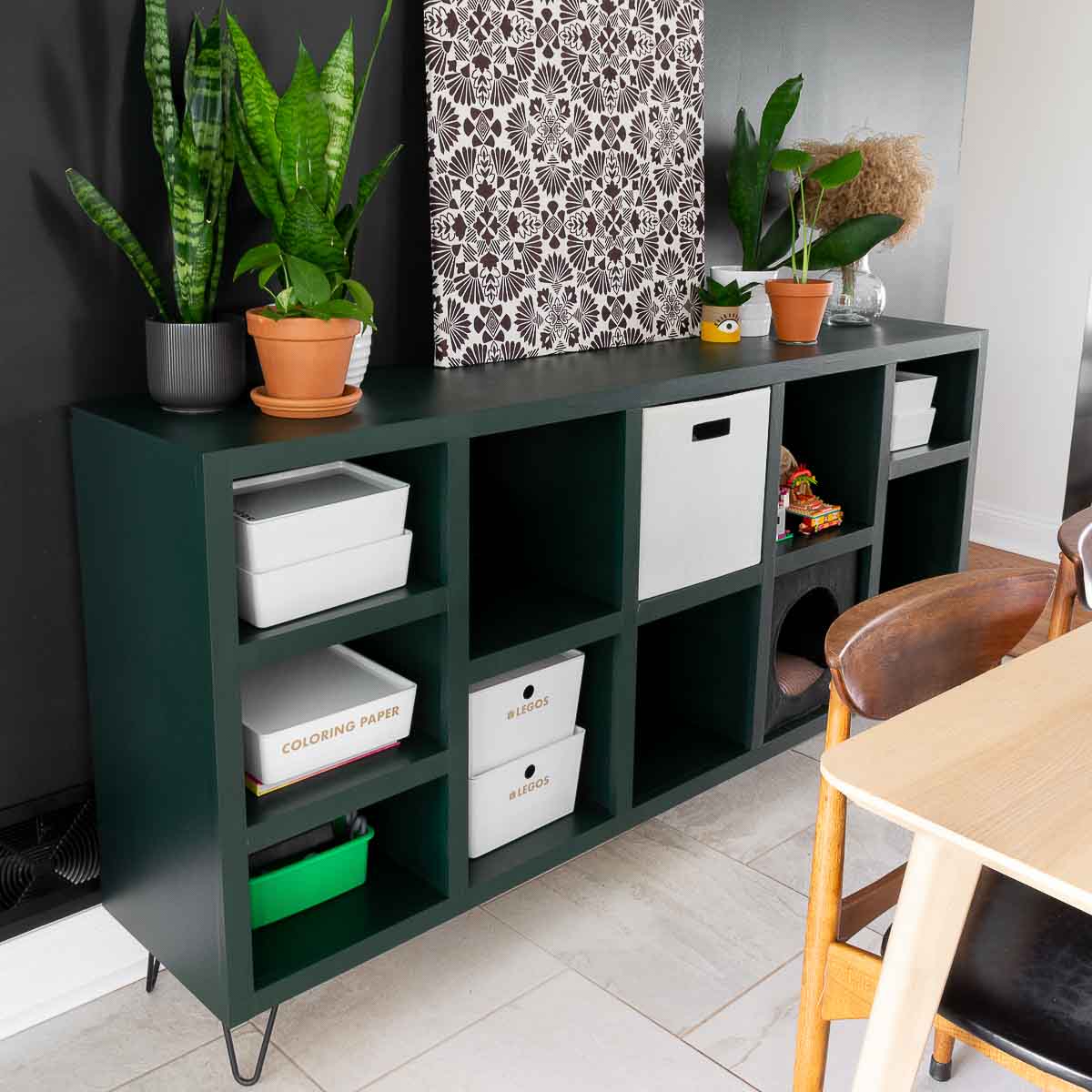 Modern cube storage unit with square cubbies and adjustable shelves on black furniture feet.