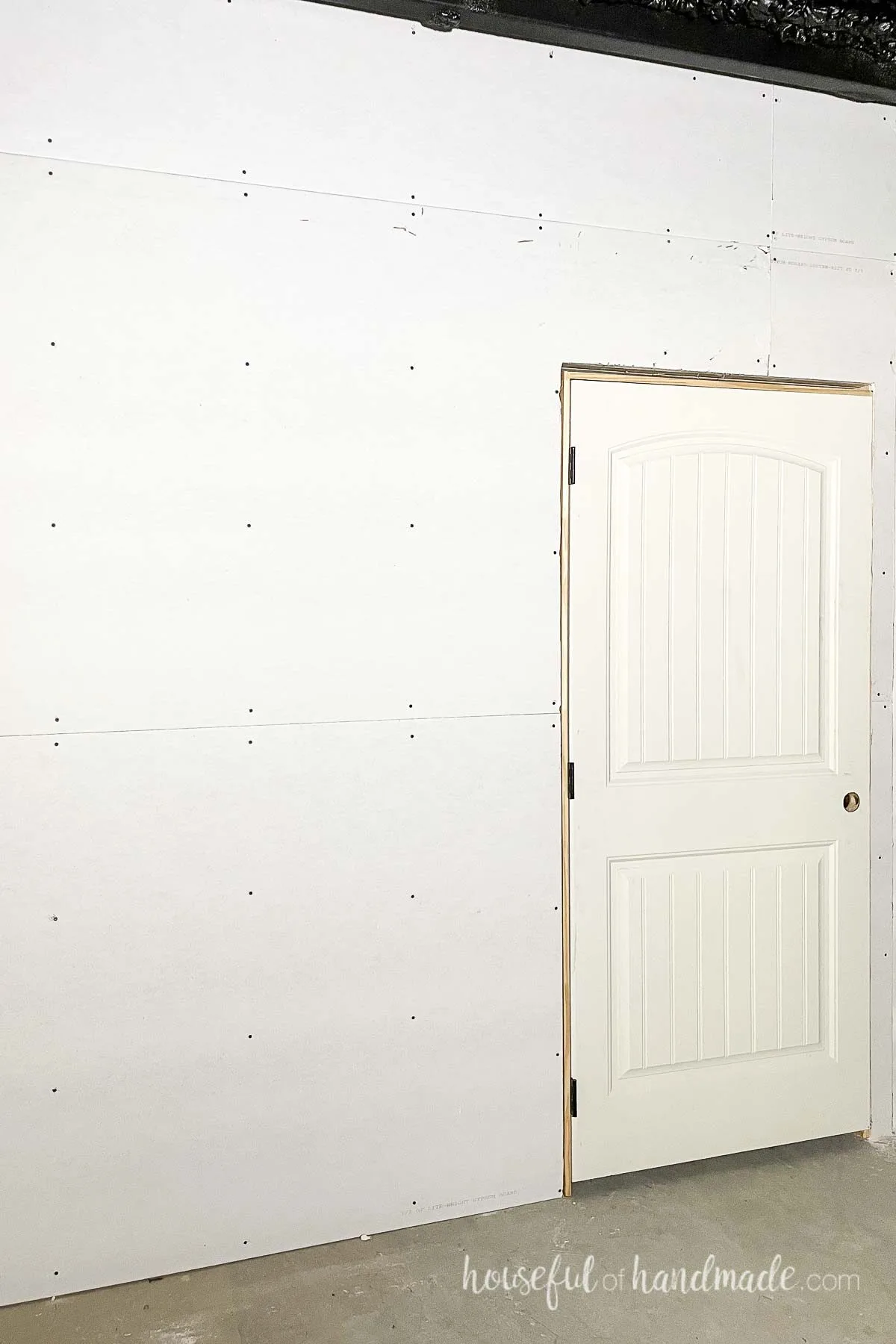 Wall covered in sheetrock around a door. 