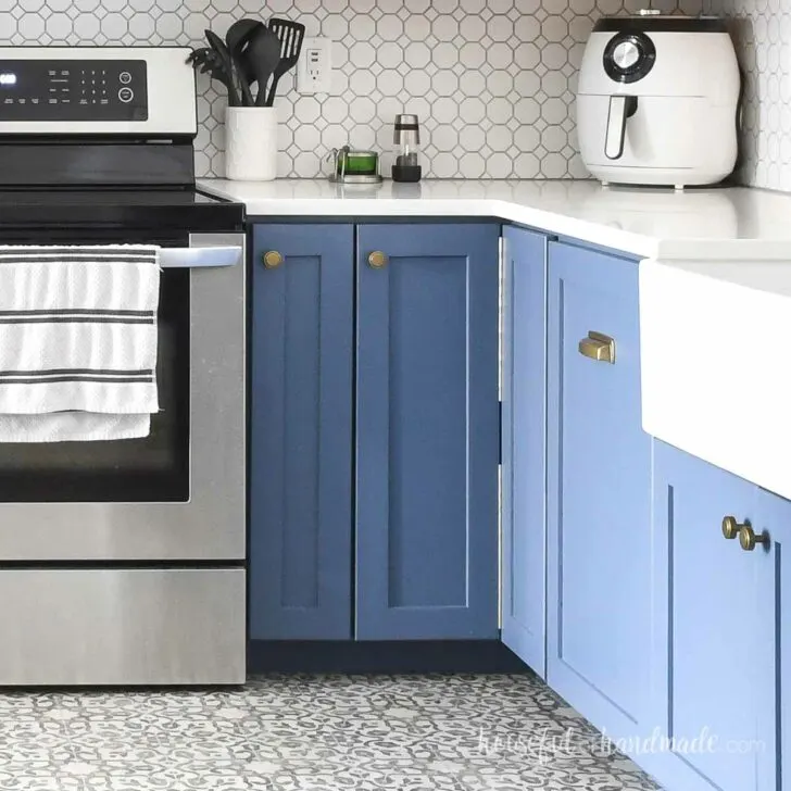 Blue base cabinets in a kitchen with a bifold corner cabinet in the corner.