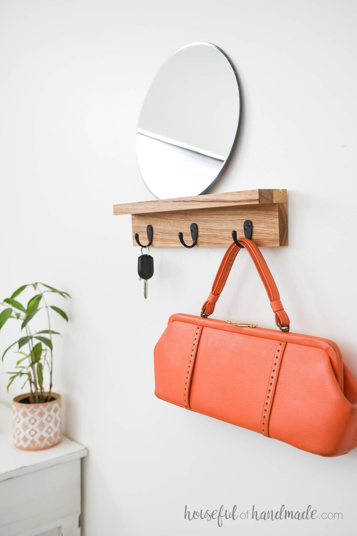 Entryway with floating wall shelf to with hooks and a round mirror. 