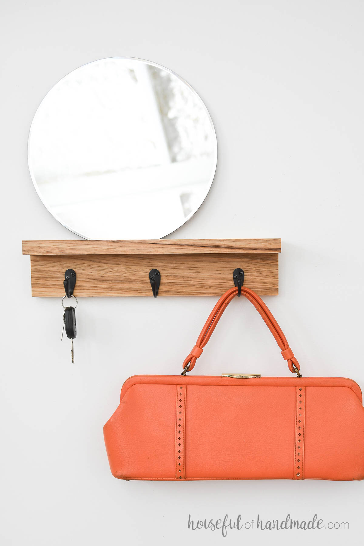 Hickory wood entrance shelf with mirror on top and keys and purse hanging on the hooks. 