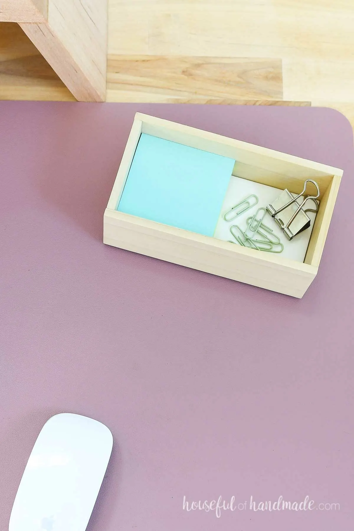 Desk organizing tray made from a white subway tile and 1/4" boards holding a pad of sticky-notes and paperclips. 