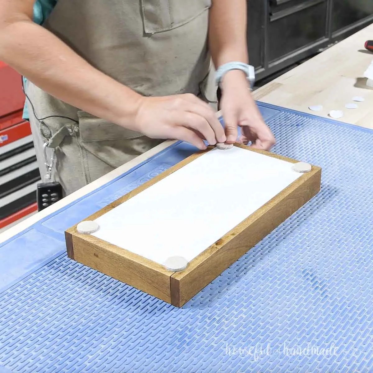 Attaching felt circles to the tray bottom for feet. 