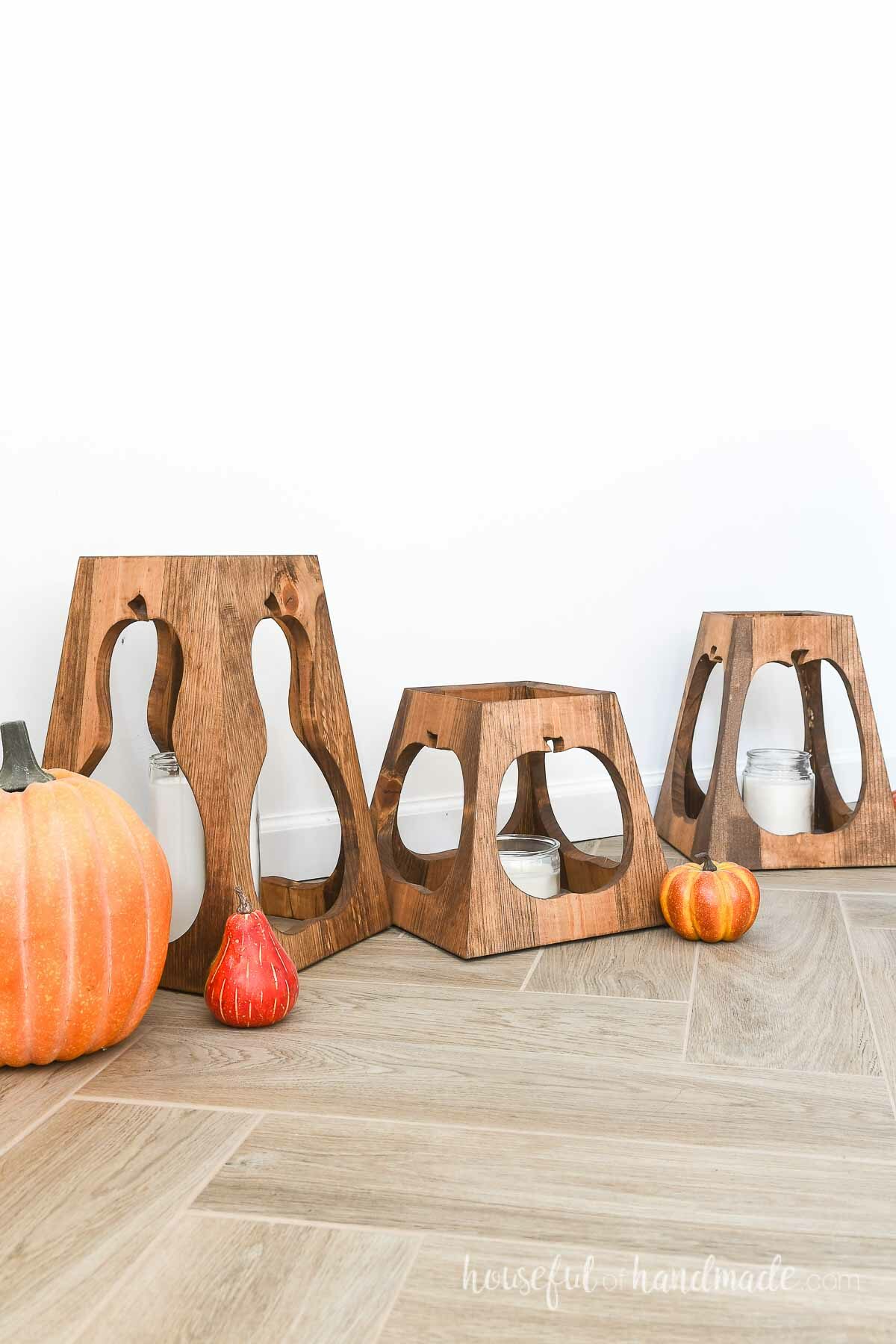 Three tapered lanterns with pumpkin shaped cut into the sides. 