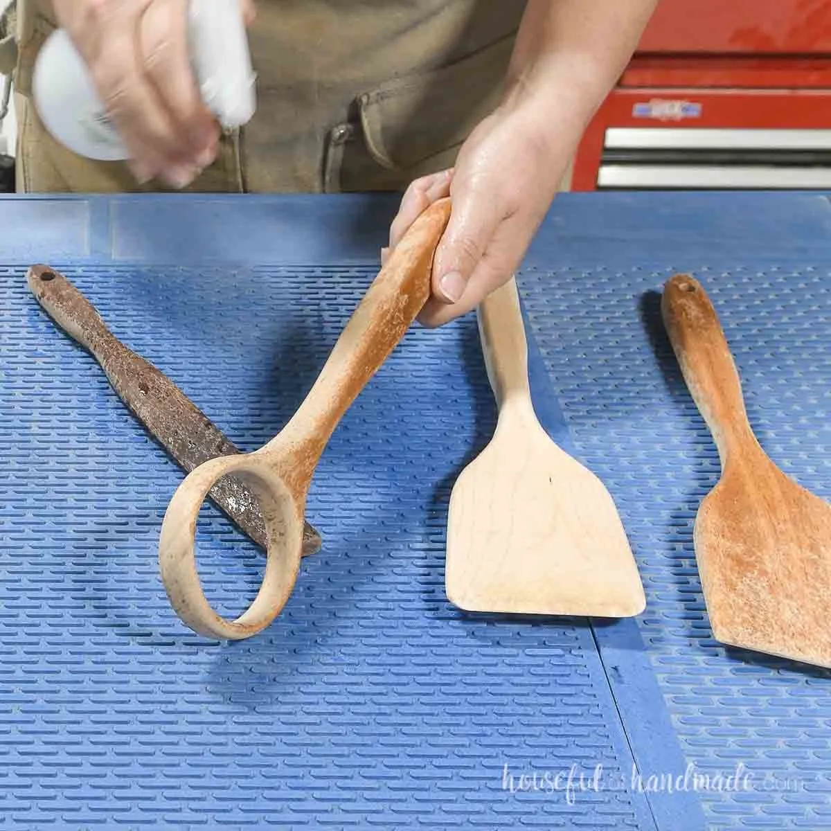 Spraying the sanded cooking utensils with water to raise the grain. 