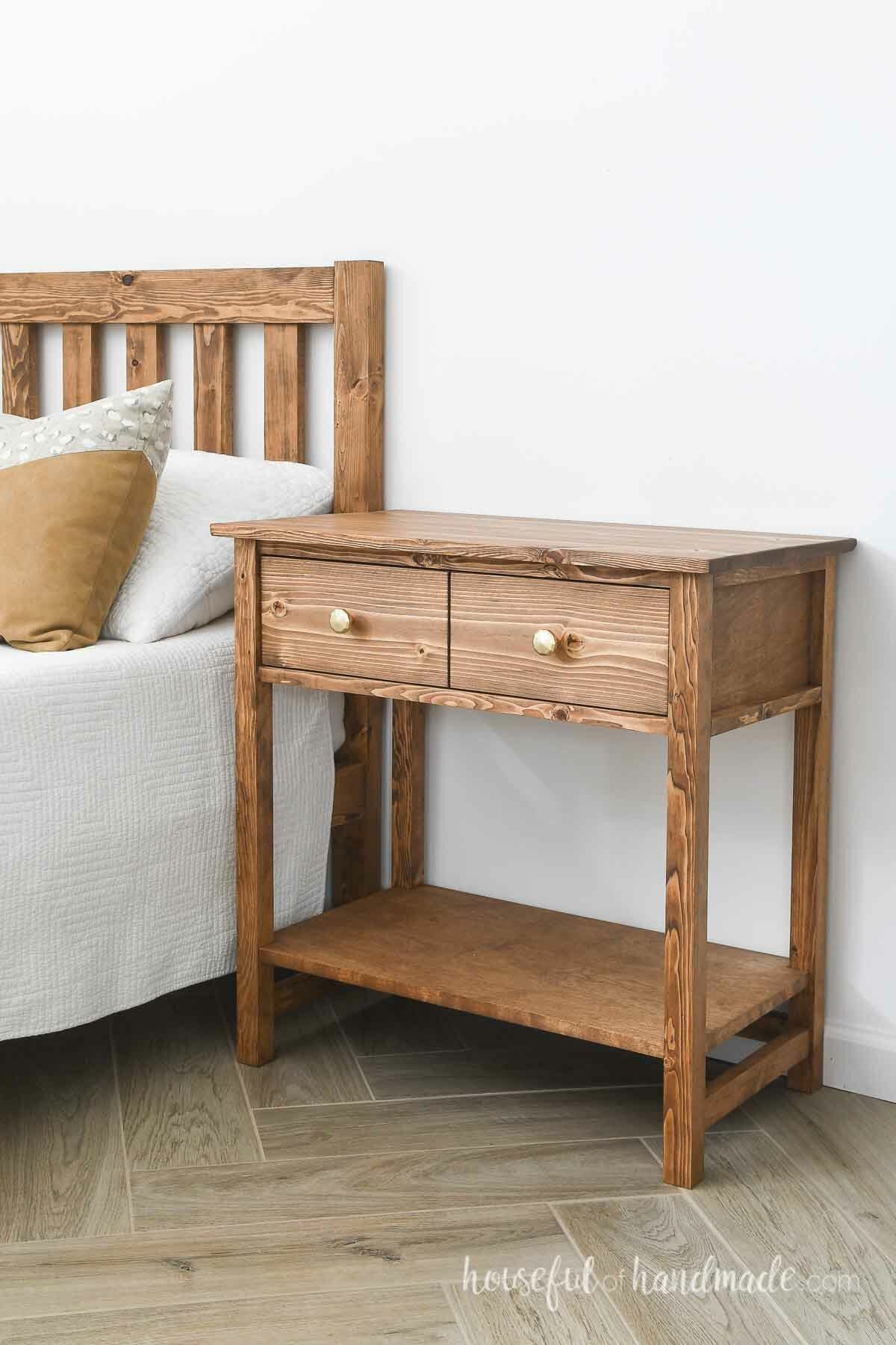 Beautiful DIY nightstand that looks like a Pottery Barn farmhouse 2 drawer nightstand next to a bed. 