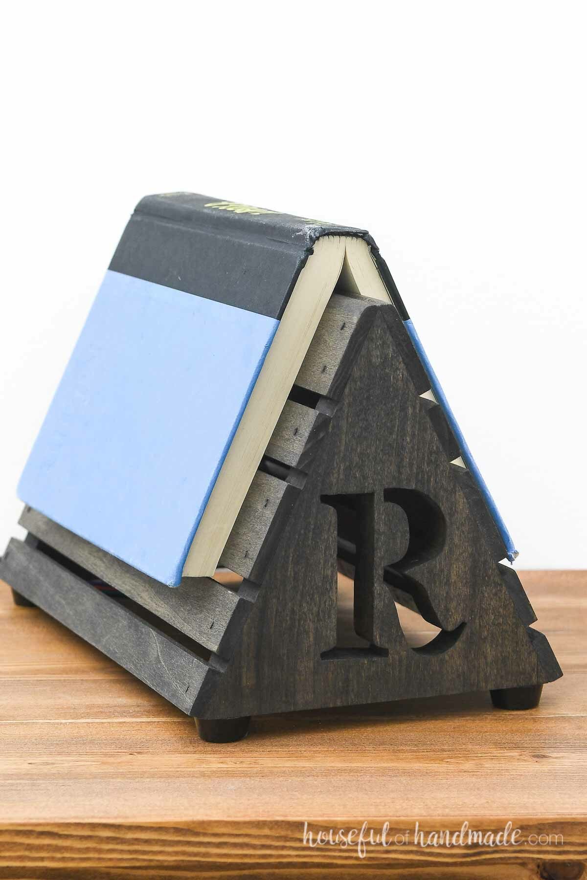 Black wood triangle book rest on a nightstand. 