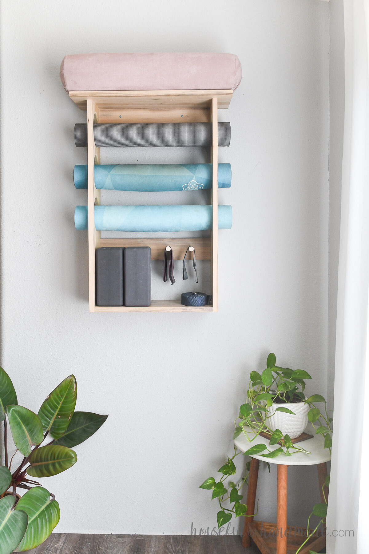 DIY exercise mat holder with shelves for additional exercise gear, mounted on a wall. 