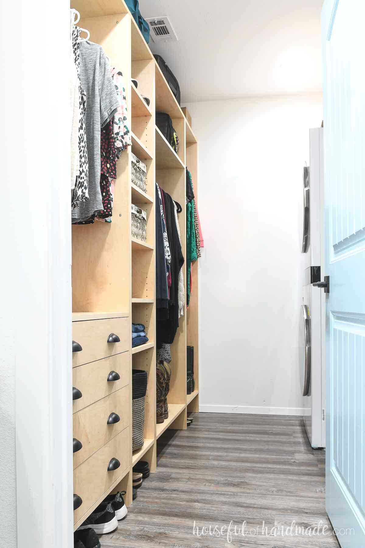 Narrow closet with wood closet system on one side and a stackable washer/dryer on the other. 