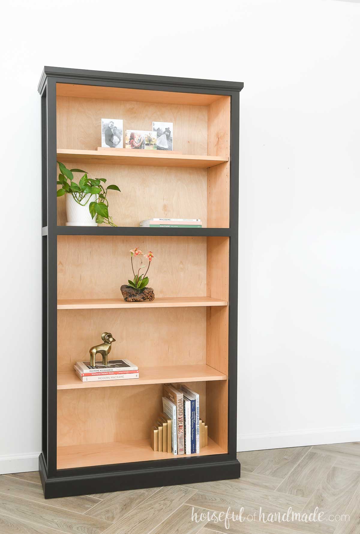 DIY tall bookcase with 5 shelves with natural wood on the inside and black paint on the outside. 