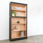 DIY tall bookcase made from plywood with wood inside and painted black outside.
