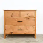DIY 4 drawer dresser with black handles up against a white wall.