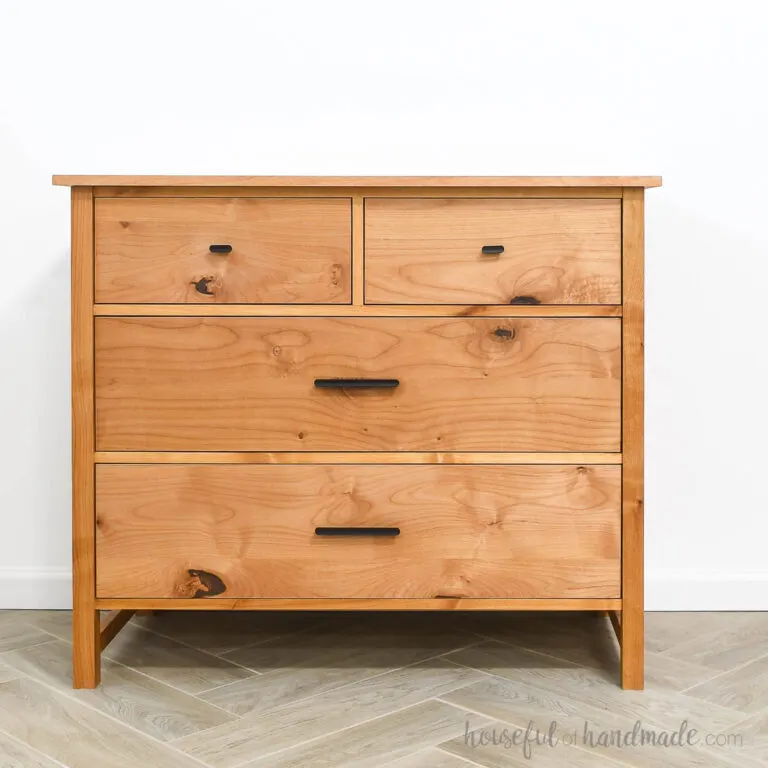 DIY 4 drawer dresser with black handles up against a white wall.