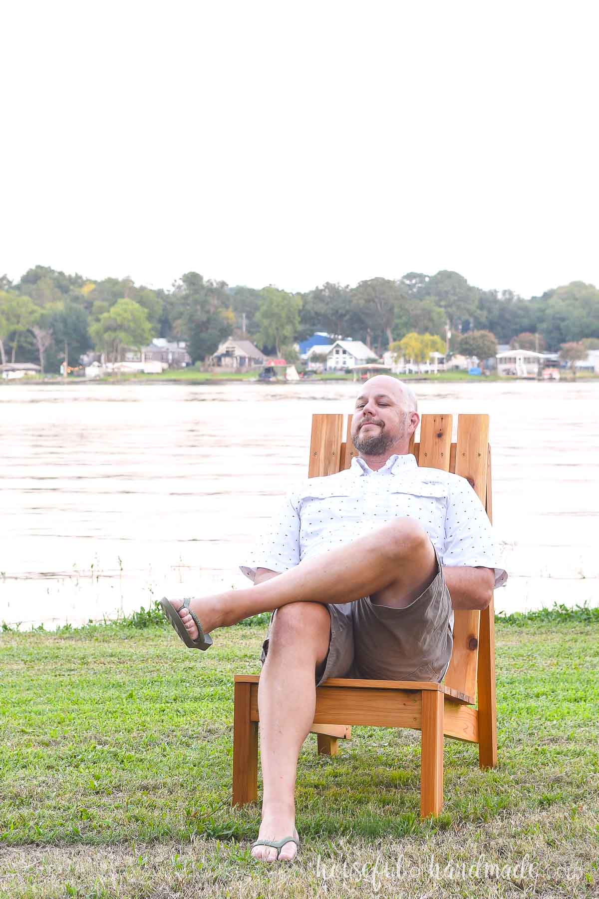 Tall man sitting in the large Adirondack chair with head resting on the back. 