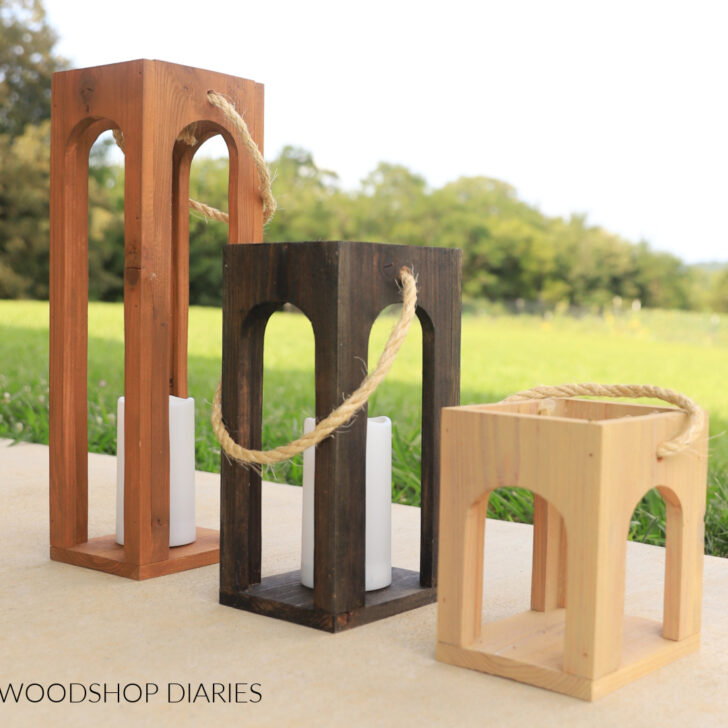 Arched wood lanterns on concrete next to a lawn.