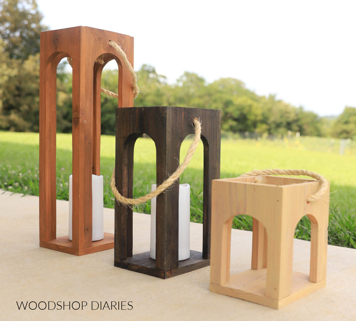 Arched wood lanterns on concrete next to a lawn.