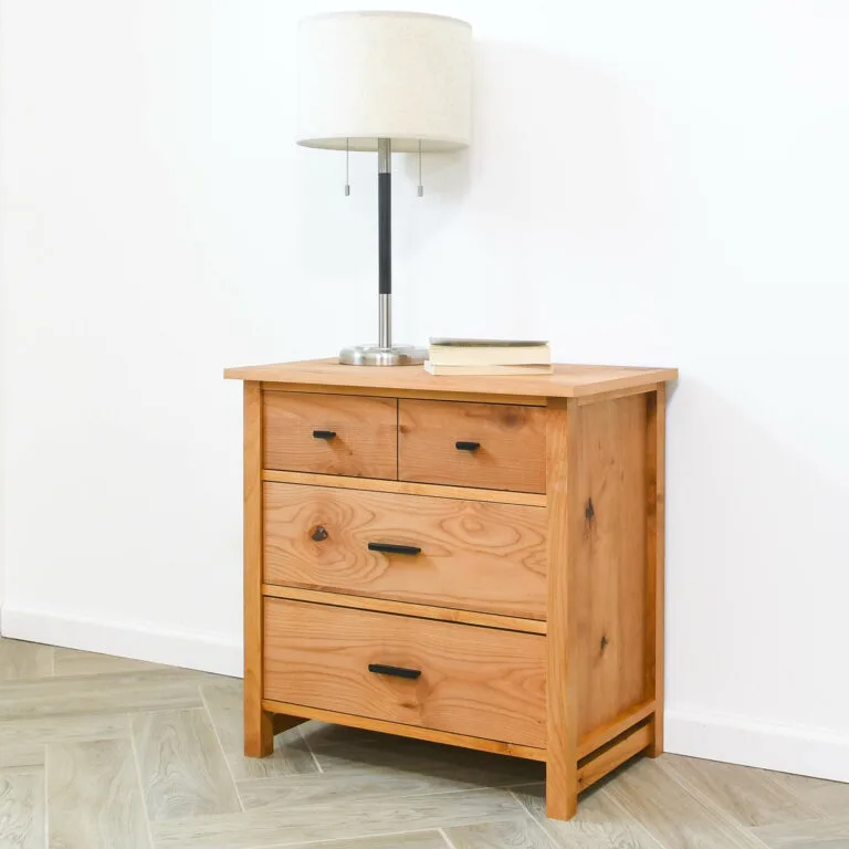 DIY 3 drawer nightstand made from alder wood with a lamp and books on top.