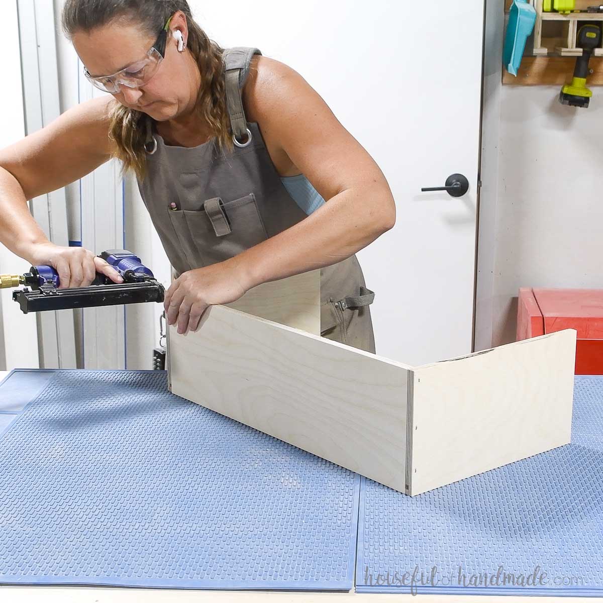 Attaching the front of the drawer box between the sides with pneumatic staples. 