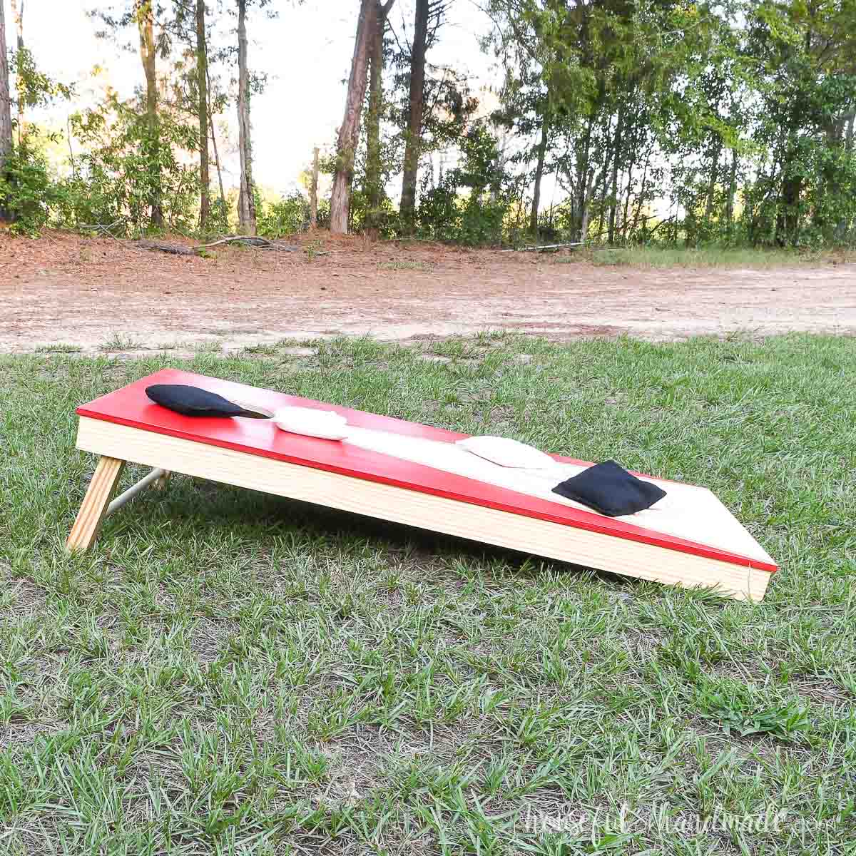 Side view of the DIY corn hole board with red painted top. 